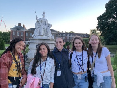 group of five students during international program in London outside of Buckingham Palace with Queen Victoria statue
