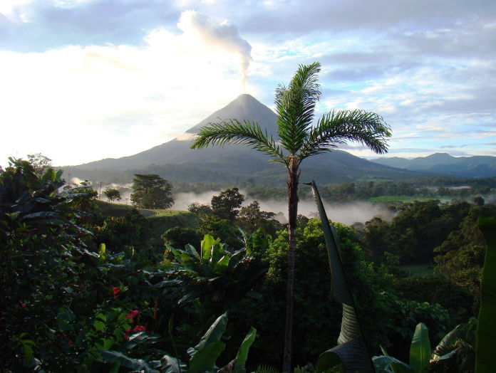 Costa Rican rainforest with active volcano in background